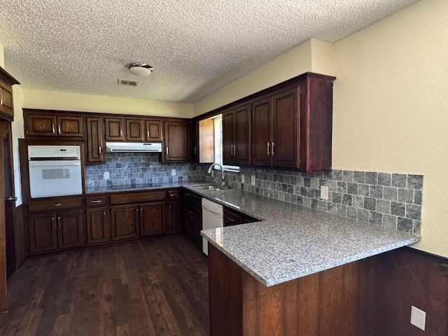 19 Mohican Cir, Shawnee, OK 74801 - kitchen with white appliances, under cabinet range hood, dark wood-style floors, a textured ceiling, and tasteful backsplash