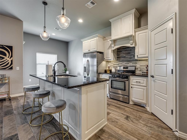 8109 NW 160th Ter, Edmond, OK 73013 - kitchen with appliances with stainless steel finishes, a sink, premium range hood, tasteful backsplash, and an island with sink