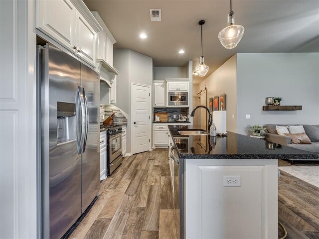 8109 NW 160th Ter, Edmond, OK 73013 - kitchen with appliances with stainless steel finishes, a sink, white cabinets, open floor plan, and backsplash