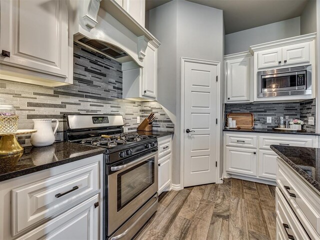 8109 NW 160th Ter, Edmond, OK 73013 - kitchen featuring stainless steel appliances, custom exhaust hood, light wood-style floors, decorative backsplash, and white cabinets