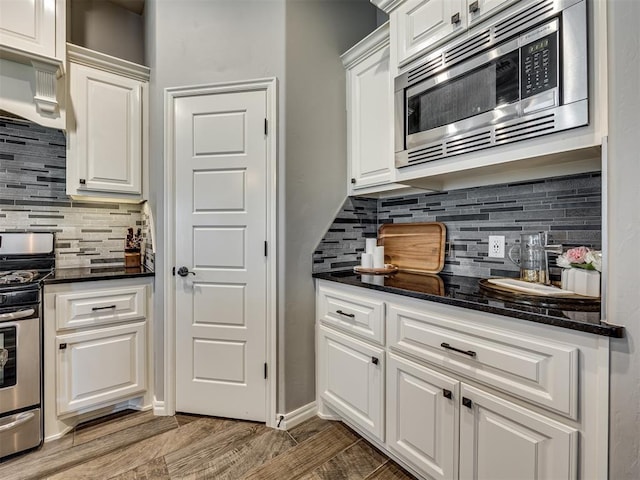 8109 NW 160th Ter, Edmond, OK 73013 - kitchen with appliances with stainless steel finishes, white cabinets, backsplash, dark stone counters, and light wood-style floors