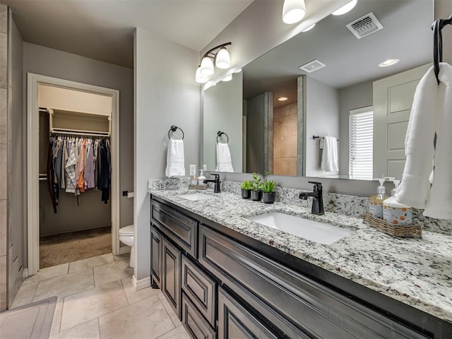 8109 NW 160th Ter, Edmond, OK 73013 - bathroom featuring toilet, double vanity, a spacious closet, tile patterned flooring, and baseboards