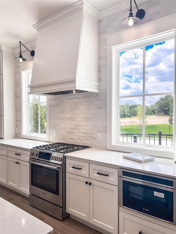 701 Montauk Way, Edmond, OK 73034 - kitchen with gas stove, custom exhaust hood, crown molding, light countertops, and backsplash