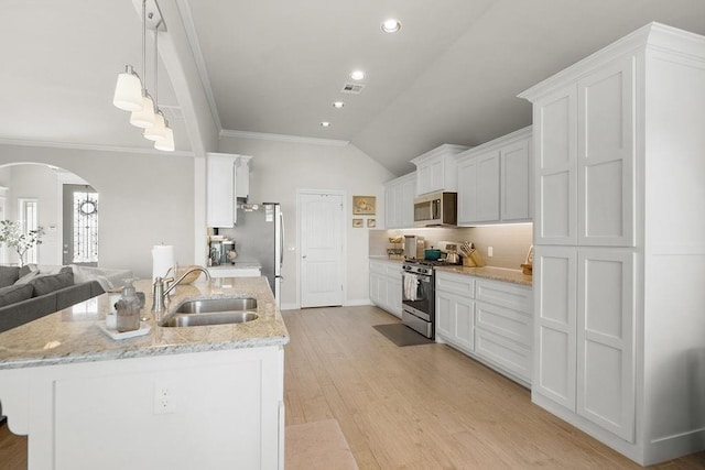 3409 Ontario Cir, Oklahoma City, OK 73160 - kitchen with appliances with stainless steel finishes, a sink, arched walkways, white cabinetry, and vaulted ceiling