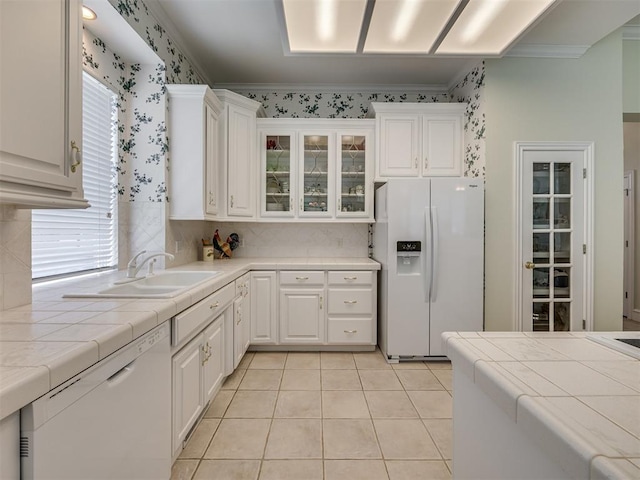 8413 NW 64th Ter, Oklahoma City, OK 73132 - kitchen with white appliances, tile countertops, a sink, ornamental molding, and white cabinets