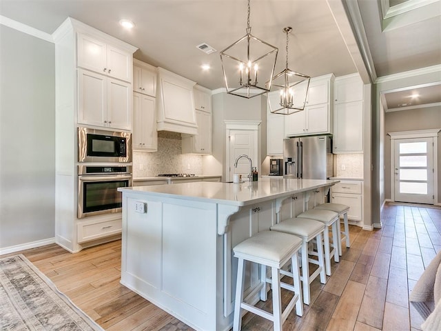 9212 NW 89th St, Yukon, OK 73099 - kitchen with stainless steel appliances, crown molding, light wood finished floors, a chandelier, and decorative backsplash