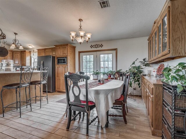 870756 S 3460th Rd, Chandler, OK 74834 - dining area with a chandelier, light wood finished floors, and a textured ceiling
