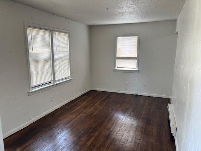 3229 NE 14th Pl, Oklahoma City, OK 73117 - empty room featuring wood finished floors, plenty of natural light, a baseboard heating unit, baseboards, and a textured ceiling