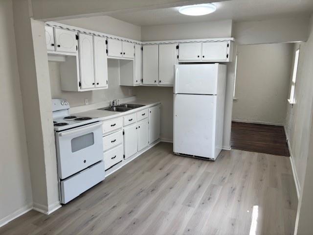 3229 NE 14th Pl, Oklahoma City, OK 73117 - kitchen with white appliances, a sink, light wood-style floors, and white cabinetry