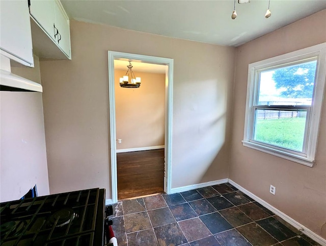 264 E Coe Dr, Midwest City, OK 73110 - unfurnished dining area with a chandelier, baseboards, and dark stone finish flooring