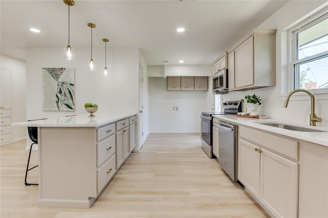 1309 NW 106th St, Oklahoma City, OK 73114 - kitchen with a sink, appliances with stainless steel finishes, a breakfast bar area, light wood finished floors, and hanging light fixtures