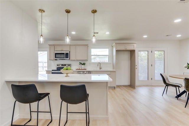 1309 NW 106th St, Oklahoma City, OK 73114 - kitchen featuring stainless steel appliances, a breakfast bar area, light countertops, decorative light fixtures, and a peninsula