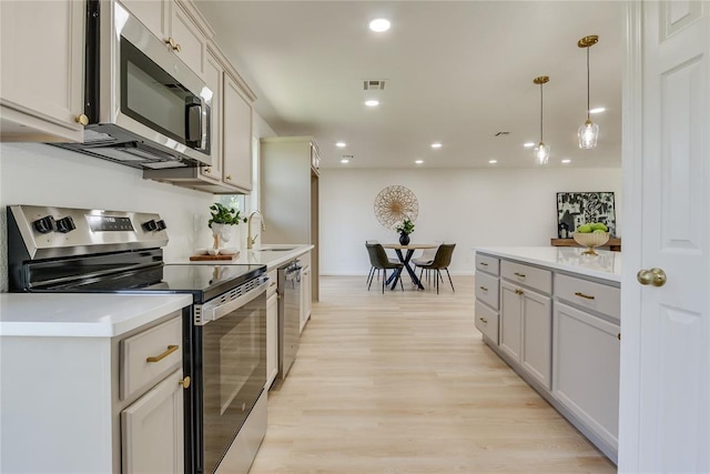 1309 NW 106th St, Oklahoma City, OK 73114 - kitchen with appliances with stainless steel finishes, a sink, light wood-style floors, light countertops, and recessed lighting