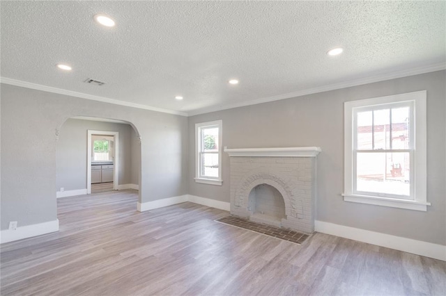 2301 N Kelham Ave, Oklahoma City, OK 73111 - unfurnished living room featuring healthy amount of natural light, arched walkways, a textured ceiling, wood finished floors, and ornamental molding