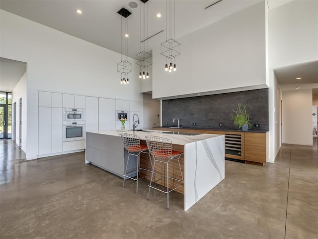 11300 N Westminster Rd, Jones, OK 73049 - kitchen featuring modern cabinets, a towering ceiling, concrete floors, wine cooler, and a large island with sink