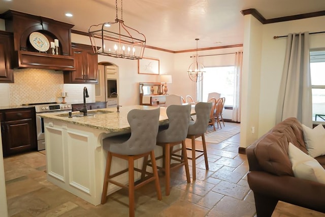 710 Isaiah Ln, Tuttle, OK 73089 - kitchen featuring stainless steel electric stove, stone tile floors, ornamental molding, healthy amount of natural light, and a chandelier