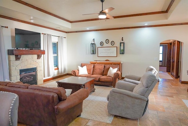 710 Isaiah Ln, Tuttle, OK 73089 - living room featuring a raised ceiling, stone tile flooring, arched walkways, healthy amount of natural light, and crown molding