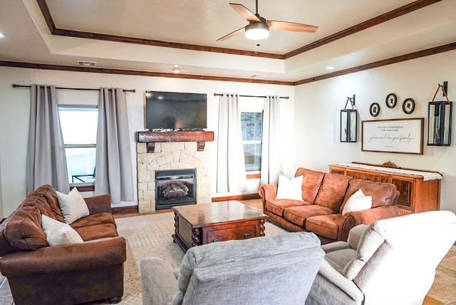 710 Isaiah Ln, Tuttle, OK 73089 - living room featuring healthy amount of natural light, ornamental molding, a raised ceiling, a ceiling fan, and a fireplace