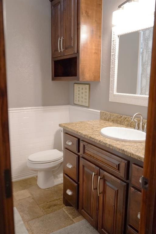 710 Isaiah Ln, Tuttle, OK 73089 - bathroom with vanity, wainscoting, toilet, and tile walls