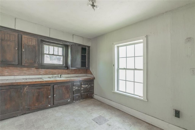 820 W Highland St, Shawnee, OK 74801 - kitchen with tile countertops, dark brown cabinetry, a sink, light floors, and baseboards