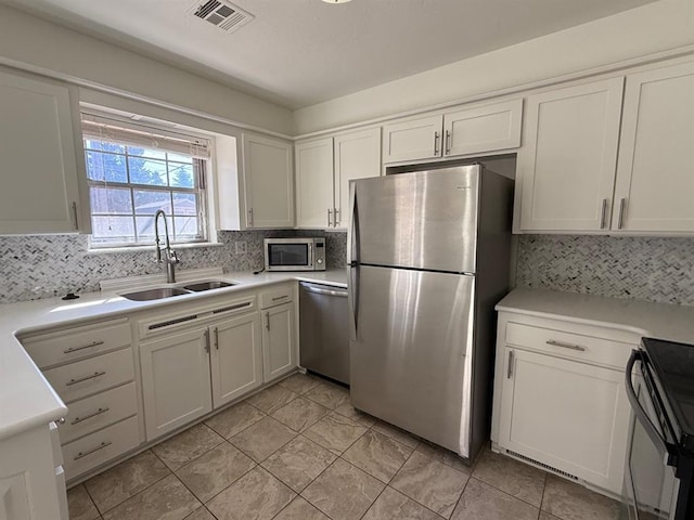 1908 NW 56th Ter, Oklahoma City, OK 73118 - kitchen with appliances with stainless steel finishes, a sink, backsplash, and white cabinets
