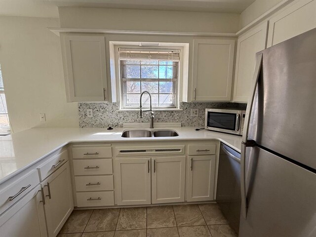 1908 NW 56th Ter, Oklahoma City, OK 73118 - kitchen featuring appliances with stainless steel finishes, a sink, decorative backsplash, light countertops, and white cabinetry