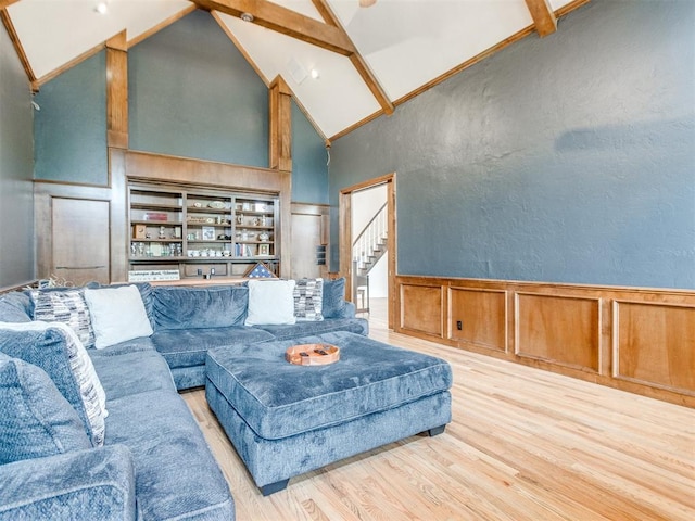 2508 Thunderwind Cir, Edmond, OK 73034 - living area featuring high vaulted ceiling, wood finished floors, wainscoting, a decorative wall, and stairs