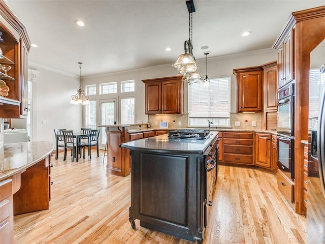 2508 Thunderwind Cir, Edmond, OK 73034 - kitchen featuring double oven, light wood-style floors, ornamental molding, brown cabinetry, and dark stone counters