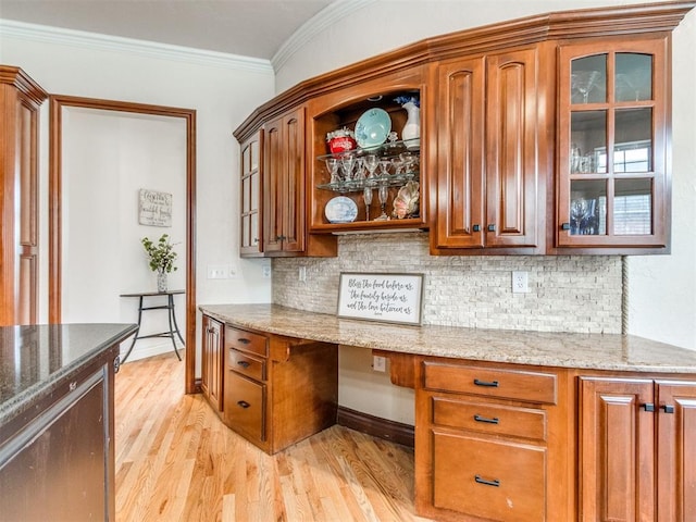 2508 Thunderwind Cir, Edmond, OK 73034 - kitchen with light wood-style flooring, tasteful backsplash, light stone counters, ornamental molding, and glass insert cabinets
