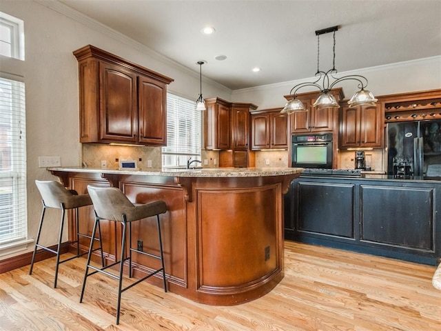 2508 Thunderwind Cir, Edmond, OK 73034 - kitchen with black appliances, light wood-type flooring, a kitchen bar, decorative light fixtures, and a peninsula