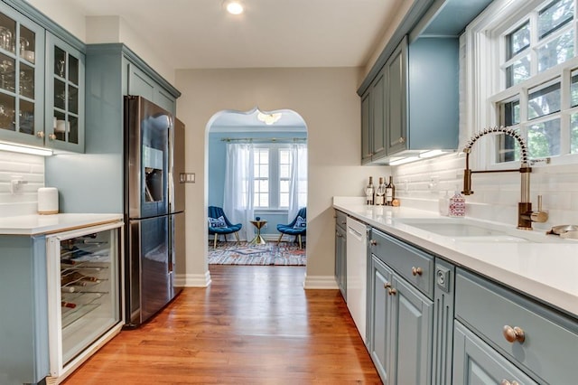 915 NW 40th St, Oklahoma City, OK 73118 - kitchen featuring beverage cooler, stainless steel fridge with ice dispenser, a sink, arched walkways, and decorative backsplash