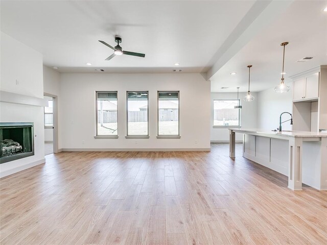 11508 NW 102nd St, Yukon, OK 73099 - unfurnished living room with ceiling fan, light wood-style flooring, recessed lighting, baseboards, and a fireplace with raised hearth
