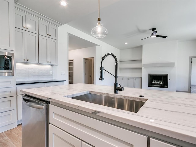 11508 NW 102nd St, Yukon, OK 73099 - kitchen featuring a sink, appliances with stainless steel finishes, light stone countertops, a fireplace, and decorative light fixtures