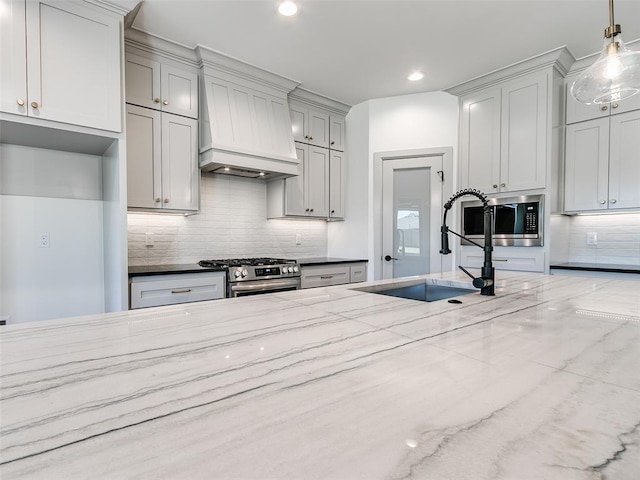 11508 NW 102nd St, Yukon, OK 73099 - kitchen featuring stainless steel appliances, premium range hood, a sink, light stone counters, and tasteful backsplash