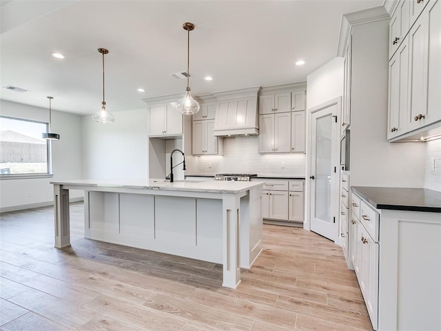 11508 NW 102nd St, Yukon, OK 73099 - kitchen with premium range hood, a sink, tasteful backsplash, light wood-style flooring, and recessed lighting