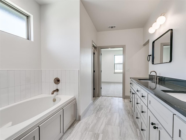 11508 NW 102nd St, Yukon, OK 73099 - bathroom with double vanity, a garden tub, plenty of natural light, and baseboards