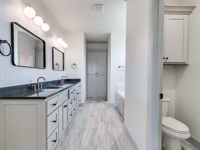 11508 NW 102nd St, Yukon, OK 73099 - full bathroom with double vanity, toilet, a bathtub, baseboards, and marble finish floors