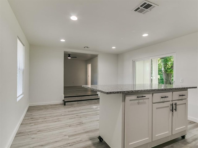 920 N Warren Ave, Oklahoma City, OK 73107 - kitchen featuring baseboards, light stone countertops, light wood-style floors, recessed lighting, and white cabinets