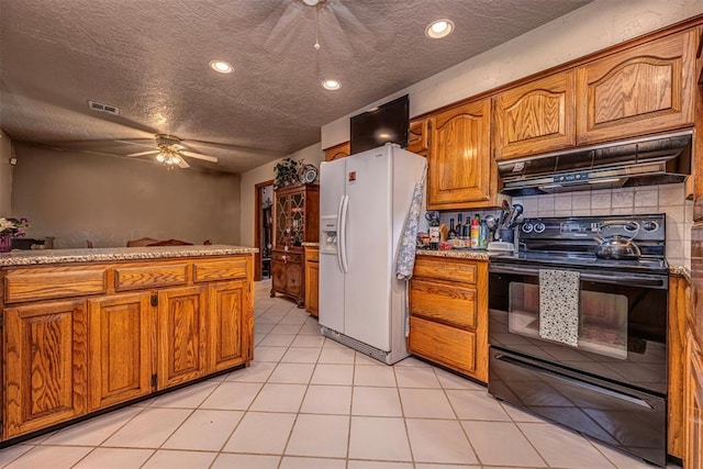 427 Foreman Ave, Norman, OK 73069 - kitchen with black electric range oven, white refrigerator with ice dispenser, under cabinet range hood, ceiling fan, and brown cabinetry
