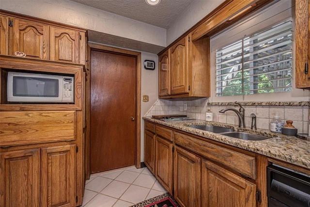 427 Foreman Ave, Norman, OK 73069 - kitchen with white microwave, a sink, tasteful backsplash, brown cabinetry, and a textured ceiling