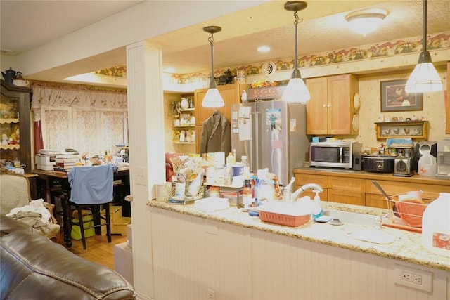 14305 N Pennsylvania Ave Unit 2C, Oklahoma City, OK 73134 - kitchen with appliances with stainless steel finishes, wood finished floors, a sink, pendant lighting, and light stone counters