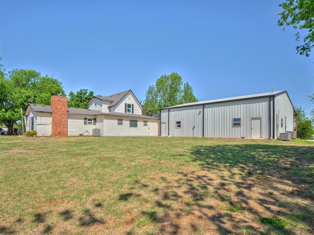 9290 N Hiwassee Rd, Jones, OK 73049 - rear view of property featuring an outbuilding, a lawn, central AC unit, and board and batten siding