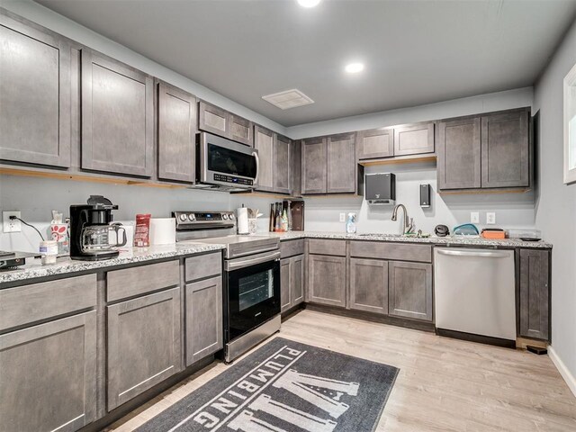 9290 N Hiwassee Rd, Jones, OK 73049 - kitchen featuring appliances with stainless steel finishes, light wood-style flooring, light stone countertops, a sink, and recessed lighting