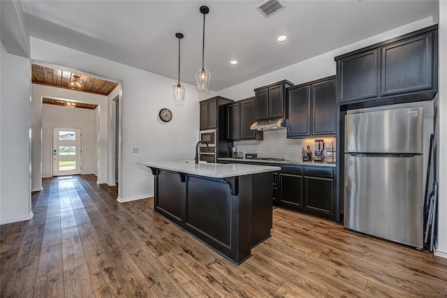 8516 Gibbs Dr, Oklahoma City, OK 73135 - kitchen with appliances with stainless steel finishes, light countertops, a center island with sink, tasteful backsplash, and a kitchen bar