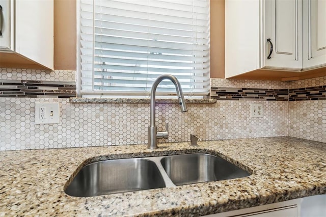 4333 NW 55th St, Oklahoma City, OK 73112 - kitchen view of a sink, decorative backsplash, light stone counters, and white cabinetry