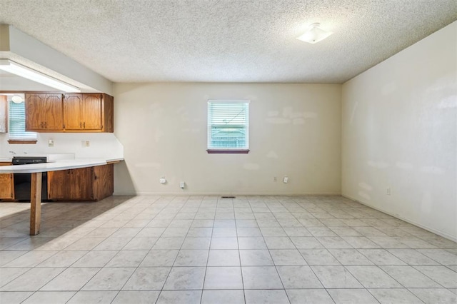 4333 NW 55th St, Oklahoma City, OK 73112 - kitchen with a textured ceiling, light countertops, brown cabinetry, and light tile patterned flooring