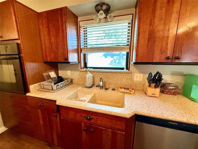 1000 Winnipeg Dr, Yukon, OK 73099 - kitchen with oven, a sink, stainless steel dishwasher, light stone counters, and brown cabinetry