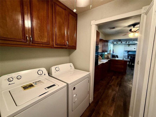 1000 Winnipeg Dr, Yukon, OK 73099 - washroom featuring cabinet space, washer and clothes dryer, dark wood-type flooring, a ceiling fan, and a large fireplace