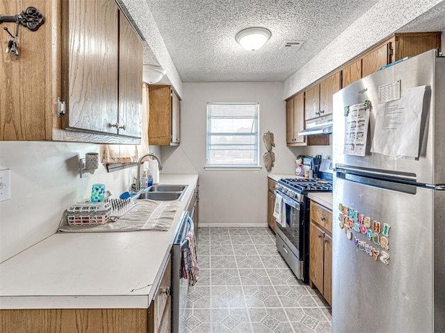 1810 Haynie Ln, Prague, OK 74864 - kitchen with appliances with stainless steel finishes, a sink, brown cabinets, light countertops, and a textured ceiling
