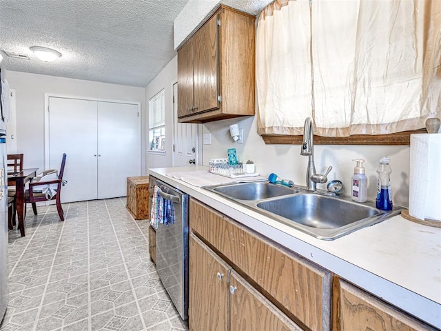 1810 Haynie Ln, Prague, OK 74864 - kitchen featuring dishwasher, a sink, light countertops, a textured ceiling, and brown cabinetry